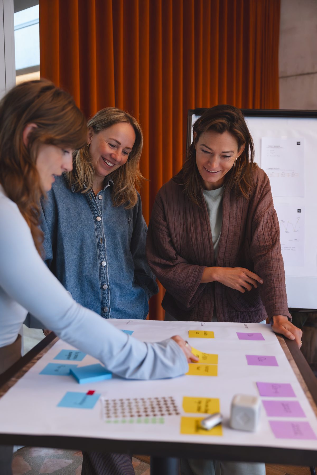 Laura van der Velden (midden) kijkt lachend mee aan de tafel met post-its tijdens de strategiedag